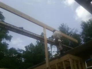 Carpenter setting a ridge beam over a new addition frame — Ice Dam Removal by Roofing Brothers in Belle Haven