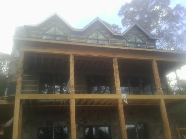 Dormers and porch framing on a large log home under construction — Roof Coating work by our crew in Belle Haven