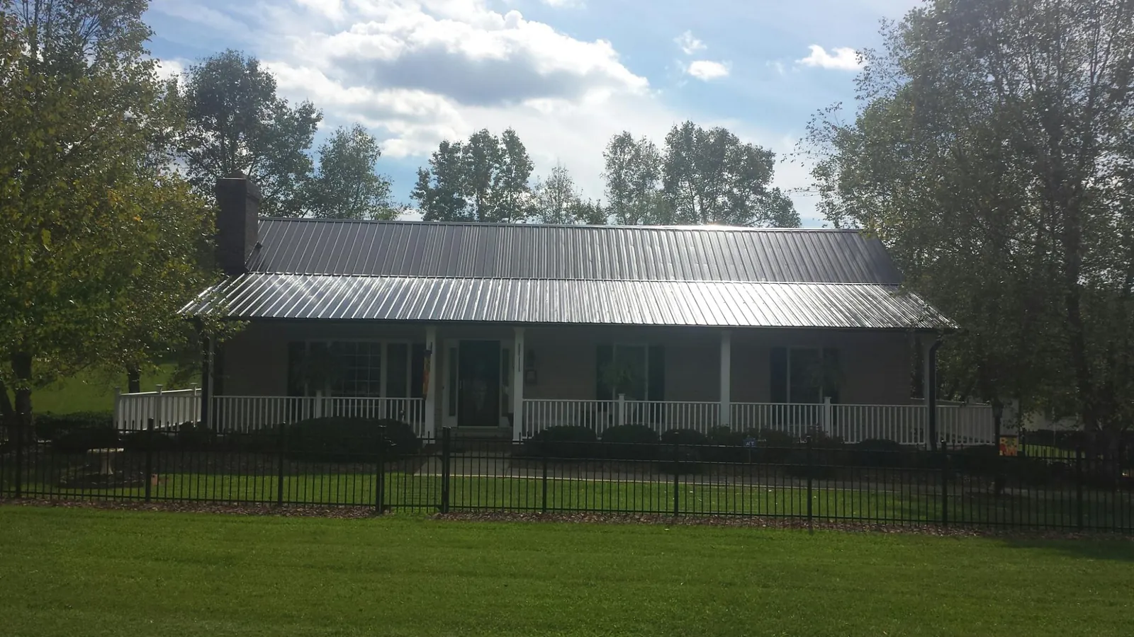Gray metal roof on a brick ranch with a full width front porch — Gutter Guard Installation work by our crew in Belle Haven