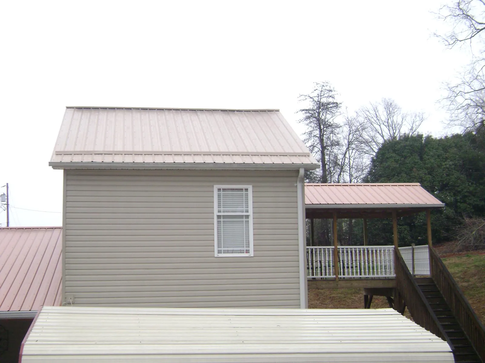 Tan metal roofs on a two story addition and attached porch, from a Roof Replacement job in Belle Haven