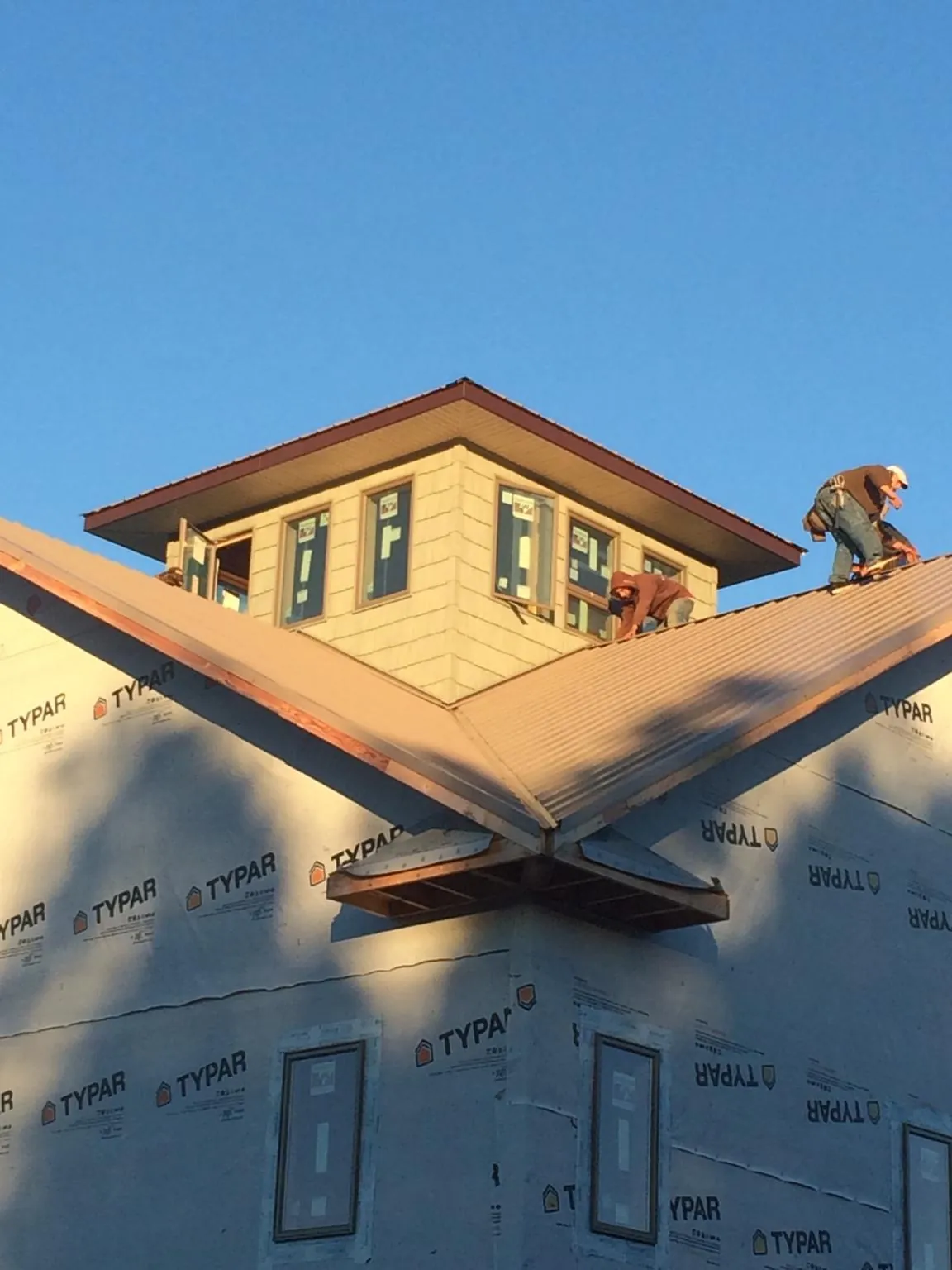 Roofers working around a rooftop cupola on a new metal roof at sunset — Roof Waterproofing in Belle Haven by Roofing Brothers